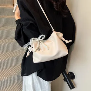 Chic pleated bucket bag in creamy white leather with pearl bow and lace detailing