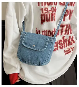 Close-up of light blue denim shoulder bag featuring a silver metal button and fine texture