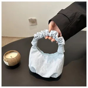Détail du sac nuage en satin bleu clair avec plis texturés et poignée plissée