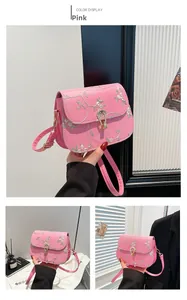 Détail d'un sac à bandoulière rose brodé de fleurs avec un fermoir doré élégant