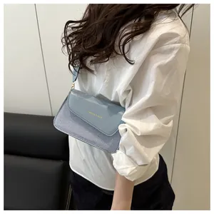 Light blue crossbody bag with textured fabric and glossy leather flap on model
