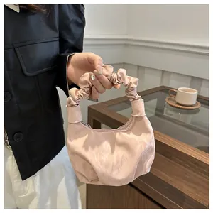 Détail du sac à main rose clair avec anse froncée et texture plissée douce et élégante
