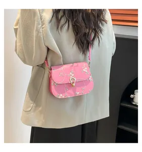 Dettaglio della borsa a sella rosa ricamata con fiori indossata da una modella