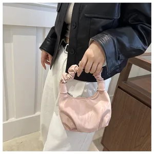 Gros plan du sac à main rose avec poignée froncée et finition en satin plissé