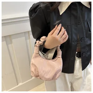Détail de l'anse froncée rose clair sur un sac en tissu texturé porté par le modèle