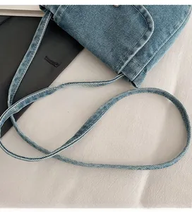Detailed shot of the blue denim shoulder bag featuring a slim adjustable long strap