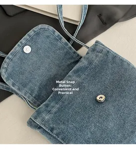 Detail of silver magnetic buckle and denim fabric texture on a crossbody bag