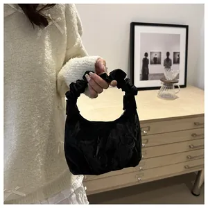 Détail du sac à main en velours noir plissé avec anse froncée porté par un mannequin