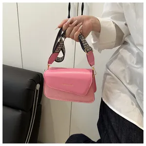 Detail of pink faux leather bag with woven texture and a black and white checkered strap