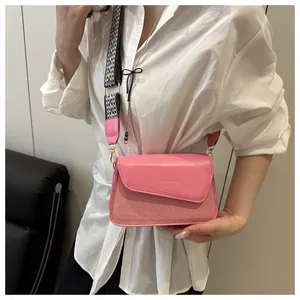 Pink patchwork crossbody bag detail with checkered strap and golden hardware