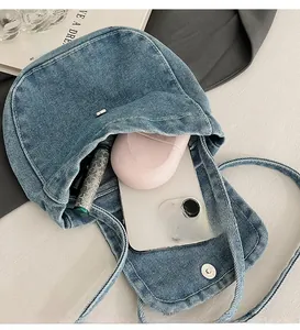 Detail view of denim crossbody bag showing storage for phone, powder, and cosmetics