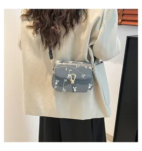 Détail du sac selle bleu-gris brodé avec boucle dorée vintage et motifs floraux