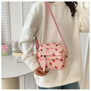 Detailed shot of pink corduroy shoulder bag with strawberry print and front pocket