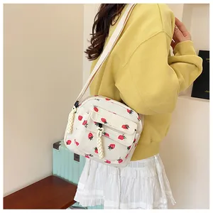 Detailed texture of white corduroy crossbody bag with strawberry print on a model