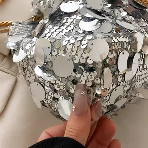 Macro shot of silver sequins on a bucket bag with metallic luster and golden chain