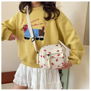 Detail view of corduroy crossbody bag with strawberry print and adjustable strap on model