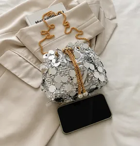 Silver sequin bucket bag size comparison with a smartphone and gold chain detail