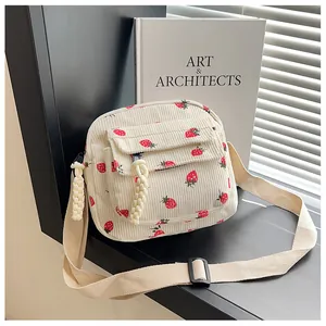 Detail of corduroy crossbody bag with strawberry print and adjustable strap