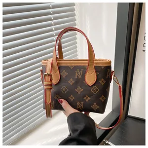 Close-up of vintage monogram bucket bag with brown leather handles and gold metal buckles