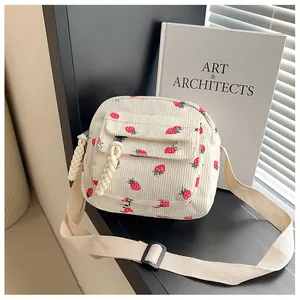 Detail of off-white corduroy crossbody bag with strawberry print and braided zipper pull
