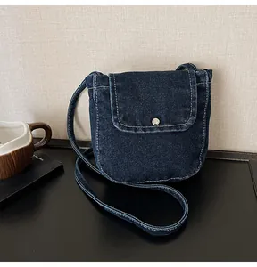 Detailed view of dark blue denim crossbody bag featuring white contrast stitching and buckle