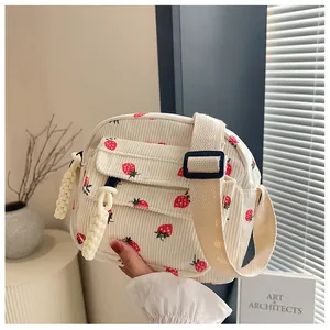 Close-up of cream corduroy crossbody bag with cute strawberry print and wide strap