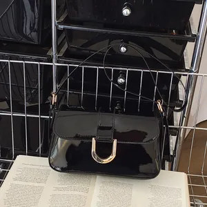 Sac sous l'aisselle en cuir verni noir avec boucle fer à cheval dorée et finition chic