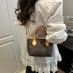 Vintage patterned bucket tote bag with leather handles and orange trim worn by a model