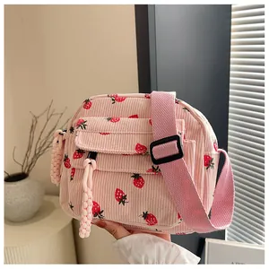 Detail of pink corduroy crossbody bag with strawberry print and adjustable strap