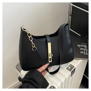 Minimalist black crescent shoulder bag with gold chain strap and metallic buckle