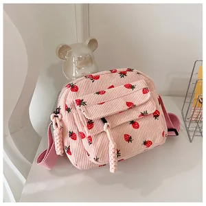 Detailed texture of pink corduroy crossbody bag with strawberry print and zipper