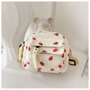 Detail of strawberry print corduroy crossbody bag with adjustable strap and woven zipper pull