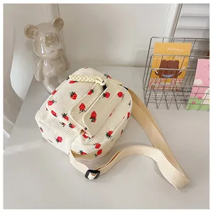 Detail of strawberry print on corduroy crossbody bag with adjustable shoulder strap