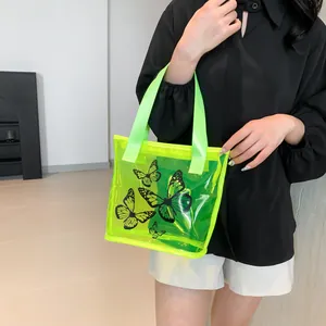 Neon green transparent PVC tote bag featuring black butterfly prints and wide strap handles