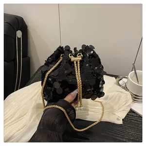 Close-up of black sequin bucket bag featuring a pearl drawstring and gold chain strap