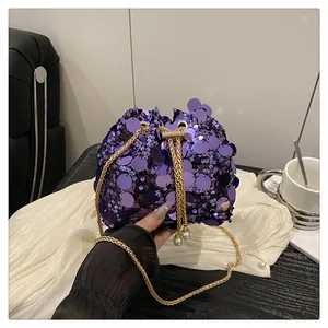 Close-up of purple sequin bucket bag with gold chain strap and pearl drawstring detail