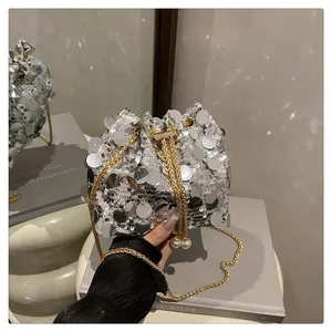 Dettaglio borsa a secchiello con paillettes argento con catena oro e ciondolo di perla
