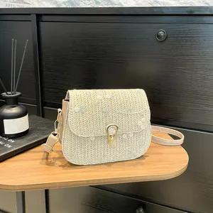 Light green woven crossbody bag with white floral embroidery and heart metal clasp