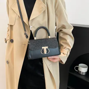 Elegant black leather handbag with glittery sequins and gold clasp shown on a trench coat