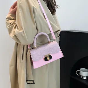 Pink crossbody handbag with glitter flap and gold lock worn by model in beige trench coat