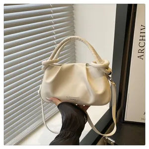 Détail de sac à main nuage crème avec poignée nouée et texture en cuir gaufré