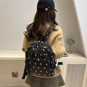 Schwarzer Nylonrucksack mit floralem Kirschblütenmuster getragen von einem Modell