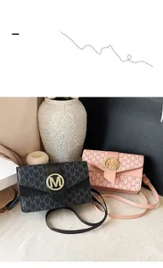 Detail of pink and black crossbody bags with monogram print and golden metal M buckle