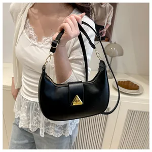 Detail of black matte crescent bag with iconic golden triangle buckle on the flap