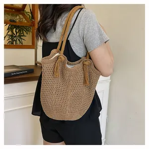 Détail du sac cabas tissé avec des pompons à franges et une maille ajourée