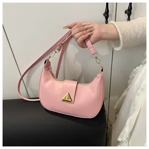 Detailed shot of pink crescent underarm bag showing gold metal clasp and leather texture
