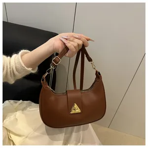 Detail of a brown crescent shoulder bag featuring a golden triangle lock and smooth finish