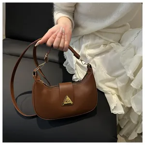 Detailed view of brown crescent shoulder bag with golden triangle metal buckle