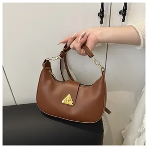 Close-up of caramel brown crescent shoulder bag with a gold triangular metal lock