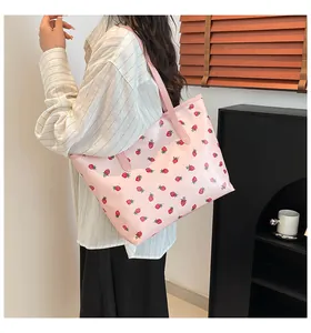 Détail d'un sac cabas rose avec motif fraises et fine bandoulière pour femme